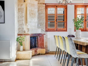 A dining area with a stone fireplace, wooden double doors, and a table with chairs.