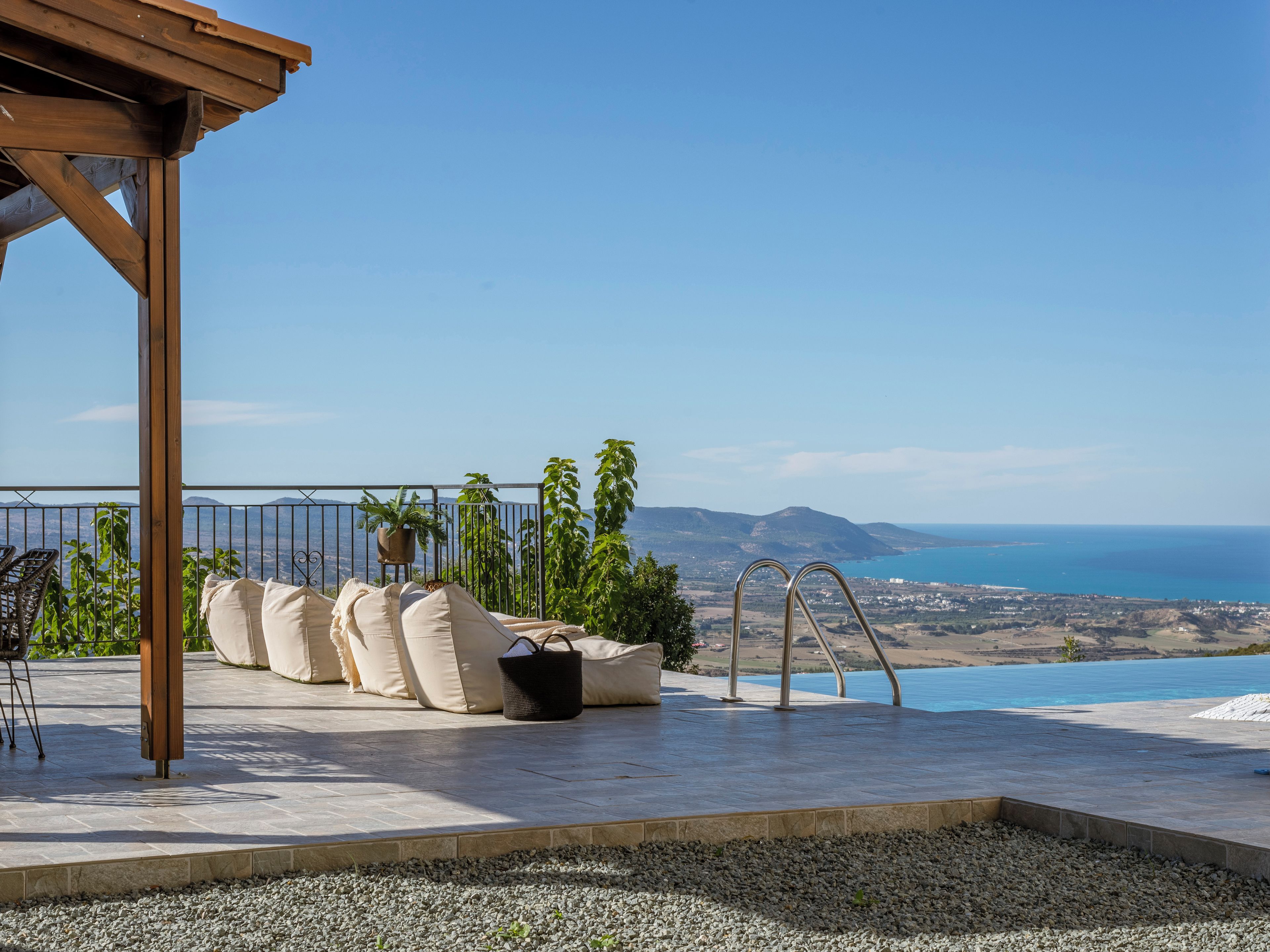 Una terraza con vistas al mar, una pérgola y mobiliario de exterior.