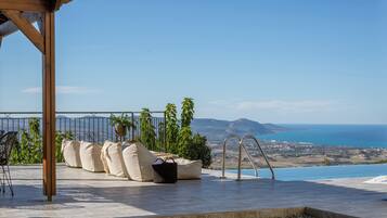 Una terraza con vistas al mar, una pérgola y mobiliario de exterior.