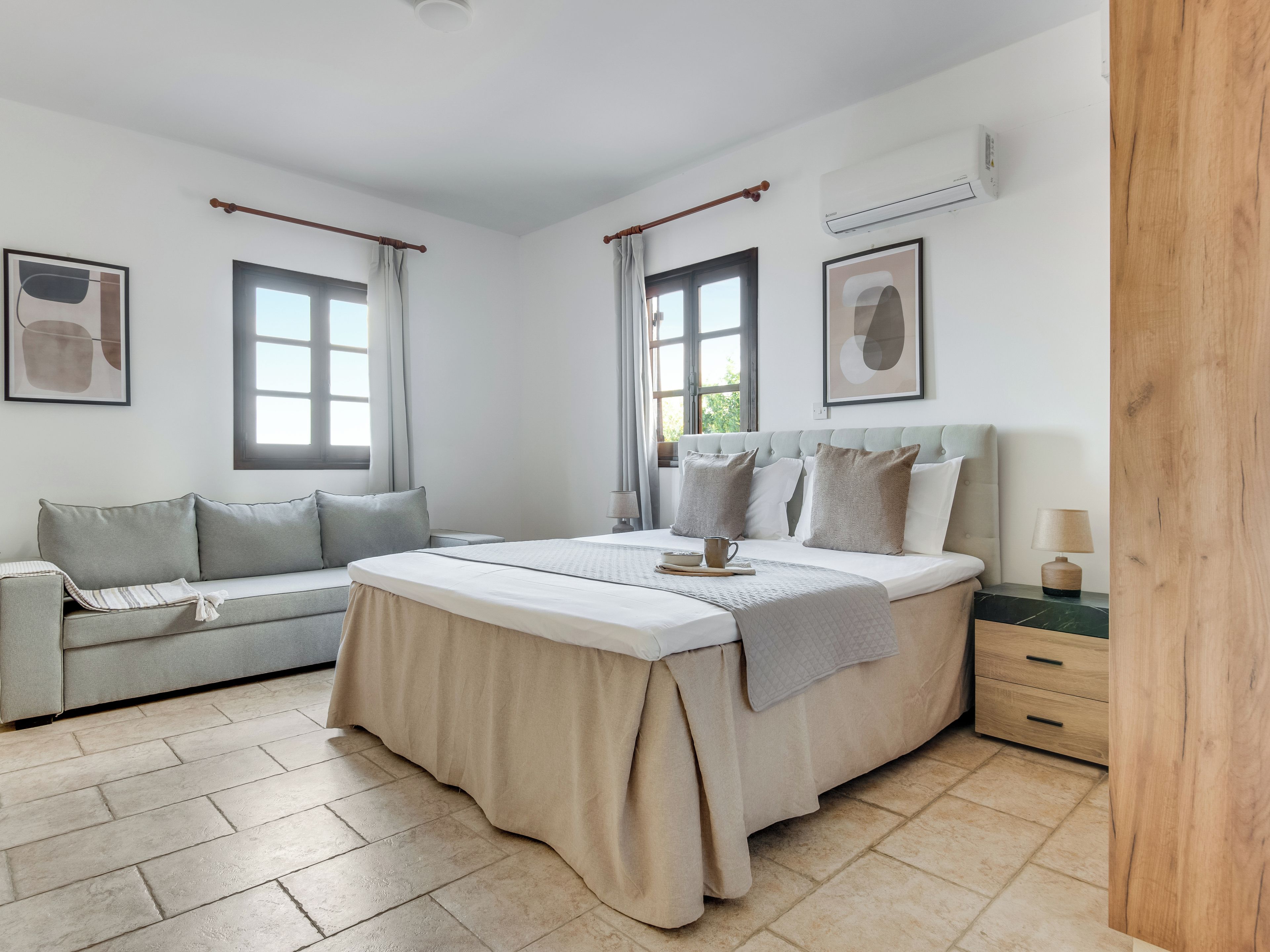 A bedroom with a bed, a sofa, a bedside table, and a nightstand.