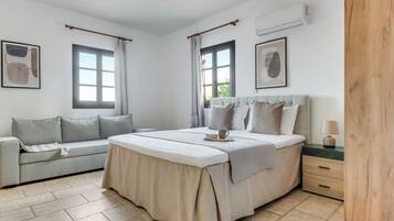 A bedroom with a bed, a sofa, a bedside table, and a nightstand.