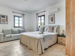 A bedroom with a bed, a sofa, a bedside table, and a nightstand.