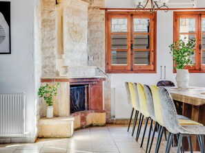 A dining area with a stone fireplace, wooden double doors, and a table with chairs.