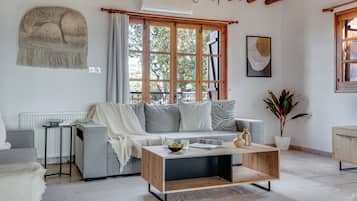 A cozy living room with a sofa, a coffee table, a radiator, a window with curtains, and a plant.