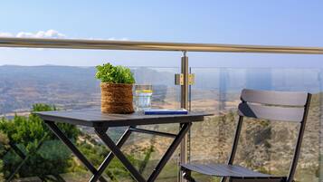 Una mesa con una planta en maceta, un vaso de agua y un libro, frente a una vista panorámica.