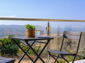 A table with a potted plant, a glass of water, and a book, set against a scenic view.