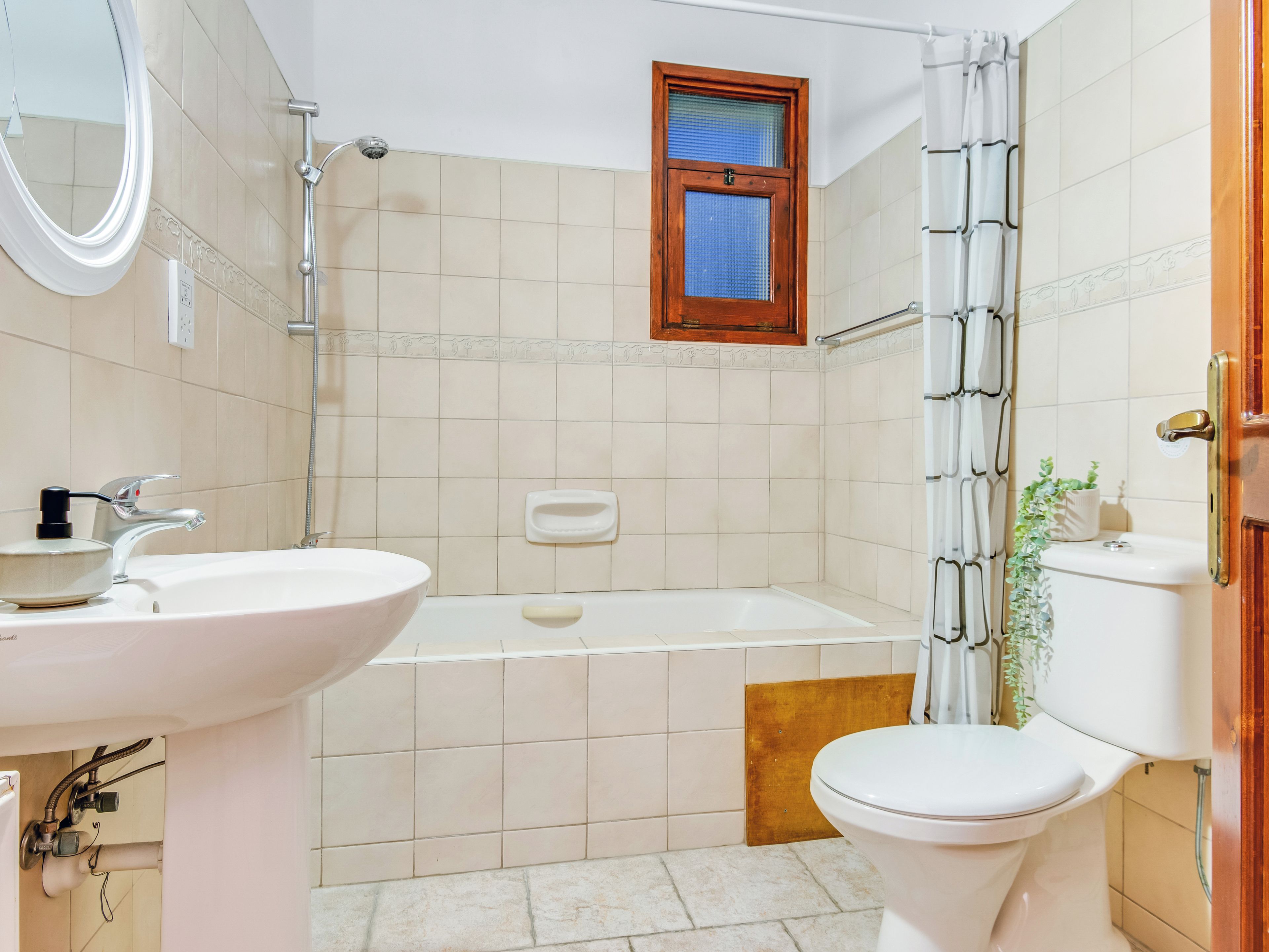 A bathroom with a sink, toilet, bathtub, shower, and a window.