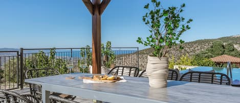 An outdoor dining area with a table, chairs, and a potted plant.