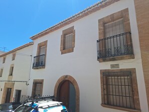 A building with multiple windows, a door, and a car parked in front.