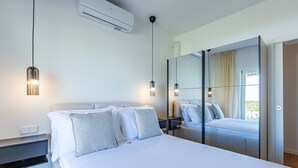 Ein modernes Schlafzimmer mit Bett, Nachttischen, einer Klimaanlage und einem großen Spiegel.