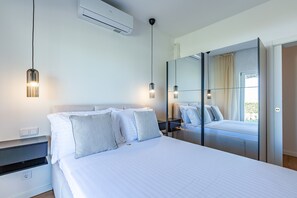 A modern bedroom with a bed, bedside tables, an air conditioner, and a large mirror. - Tavira Sweet - Convento das Bernardas (Tavira)