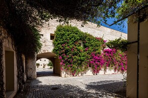 A cobblestone street with a stone archway, surrounded by buildings with flowering vines. - Tavira Sweet - Convento das Bernardas (Tavira)