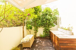 A wooden deck with a bench, a planter with plants, and a wall with climbing plants. - Serene Haven - Refúgio do Forte (Cabanas de tavira)