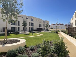 A modern building with a courtyard, surrounded by greenery and a clear sky. - Serene Haven - Refúgio do Forte (Cabanas de tavira)