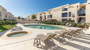 Et moderne hotel med poolområde, liggestole og jacuzzi.