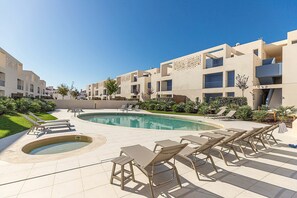 Ein modernes Hotel mit Poolbereich, Liegestühlen und Whirlpool.