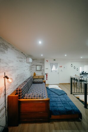 A room with a bed, a small table, a sofa, and a kitchenette. - Casa Santana - Uva Douro Houses (Casais do Douro)