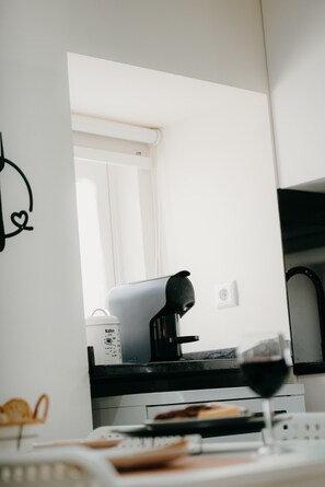 A kitchen with a coffee machine, a glass of red wine, and a white countertop. - Casa Santana - Uva Douro Houses (Casais do Douro)