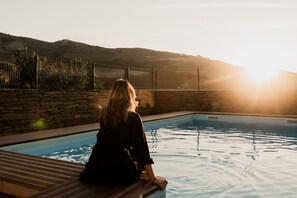 A person seated by a pool with a view of a mountainous landscape and a fence. - Casa de Xisto - Uva Douro Houses (Ervedosa do Douro)