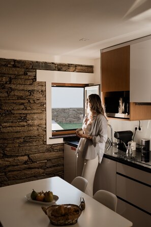 A modern kitchen with a stone wall, a large window, and a view of the sea. - Casa de Xisto - Uva Douro Houses (Ervedosa do Douro)