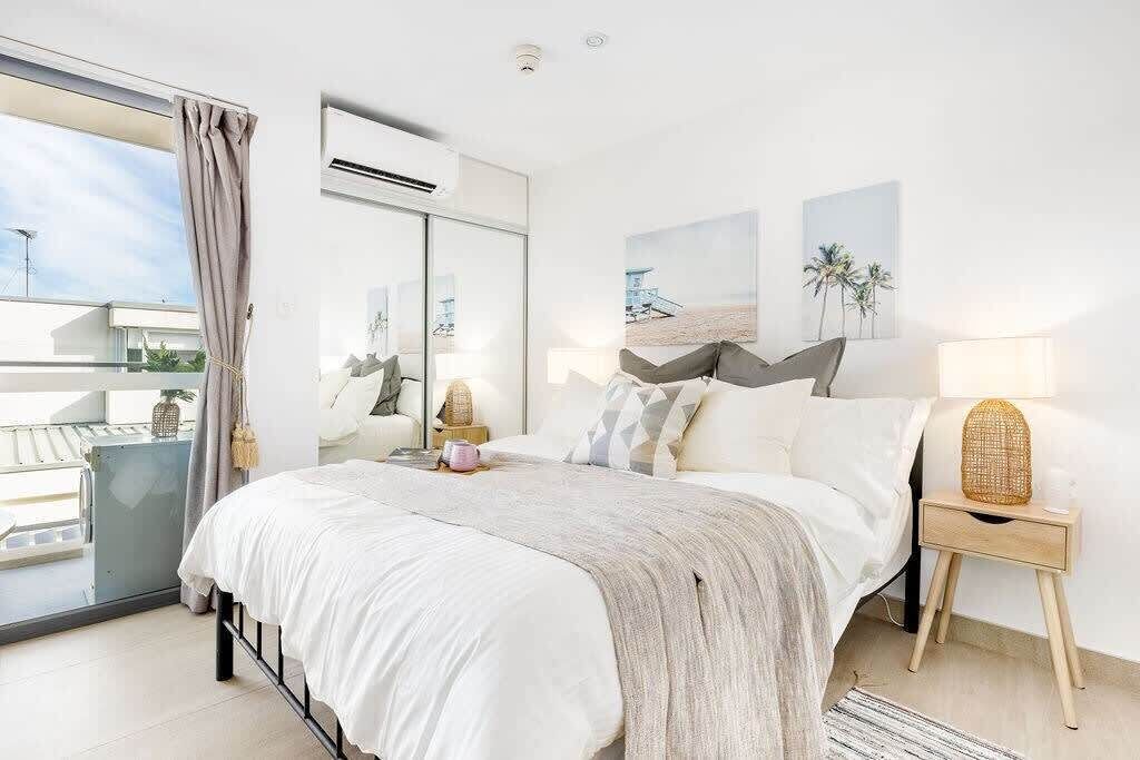 Ein modernes Schlafzimmer mit einem großen Bett, einem Balkon und Blick zum Himmel.