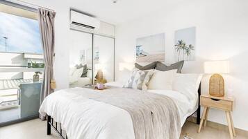 Una camera da letto moderna con un letto grande, un balcone e vista sul cielo.