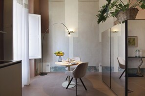 Ein moderner Essbereich mit einem runden Tisch, Stühlen, einer Stehlampe und einem Blumenstrauß.