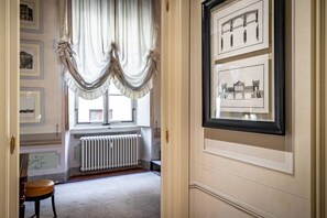Ein Flur mit einem gerahmten architektonischen Entwurf an der Wand, einem Heizkörper und einem mit Vorhängen drapierten Fenster.