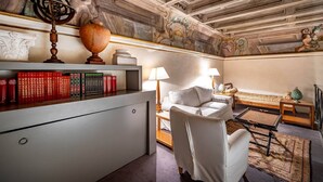 A room with a desk, books, a lamp, a sofa, and a decorative ceiling. - Vigna Vecchia (Florence)