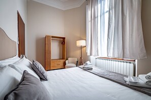 A hotel room with a bed, a chair, a wooden wardrobe, a lamp, and a window with curtains. - Poggi 22 (Florence)
