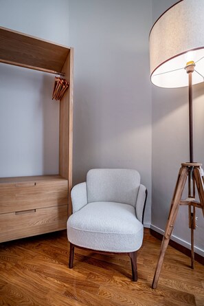 A room with a wooden bench, a light grey armchair, and a floor lamp. - Poggi 22 (Florence)