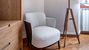 A room with a wooden wardrobe, a grey armchair, a floor lamp, and a radiator. - Poggi 22 (Florence)