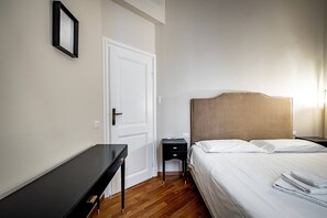 A bedroom with a bed, bedside table, nightstand, and a door. - Poggi 22 (Florence)