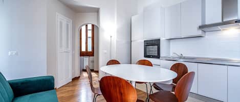 Una cocina moderna con armarios blancos, una mesa redonda de comedor y sillas de madera.