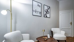 A modern room with two white armchairs, a wooden coffee table, a gold floor lamp, and two framed artworks on the wall. - Poggi 22 (Florence)