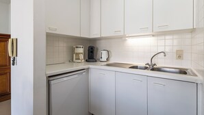 Eine moderne Küche mit weißen Schränken, einem Geschirrspüler, einer Kaffeemaschine und einem Spülbecken.