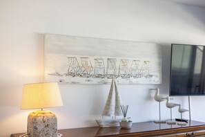 Ein Zimmer mit einem Segelbootgemälde, einer Lampe, einem dekorativen Segelbootmodell und einem Fernseher.