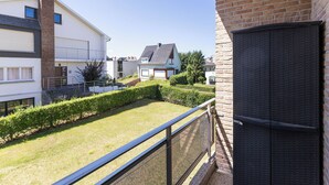 Ein Wohngebiet mit modernen Häusern, einem gepflegten Rasen und einem Balkon mit Metallgeländer.