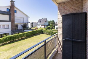 A residential area with modern houses, a well-maintained lawn, and a balcony with a metal railing. - Ravelingen 0101+ G * (Koksijde)