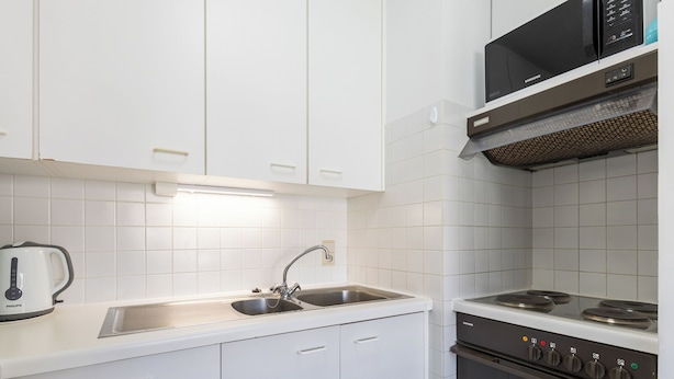 A modern kitchen with white cabinets, a stainless steel sink, a Siemens microwave, and a Siemens oven.