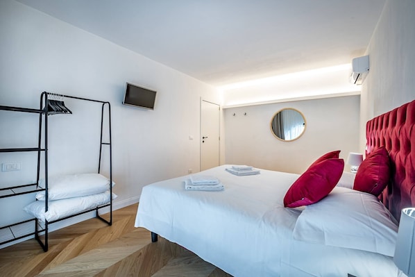 Una habitación de hotel con literas, un televisor de pantalla plana, un espejo redondo y un cabecero rojo.