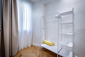 A room with a white metal bunk bed, a white shelf unit, and a yellow object on the shelf. - Bolognese 4 (Florence)