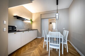 A modern kitchen with white cabinets, a black range hood, and a herringbone wood floor. - Bolognese 4 (Florence)