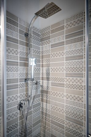 A shower with a geometric tile pattern and a modern showerhead. - Bolognese 4 (Florence)
