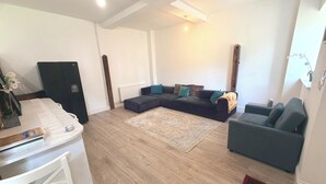 A modern living room with a sectional sofa, a coffee table, and a dining area with a white table and chairs.
