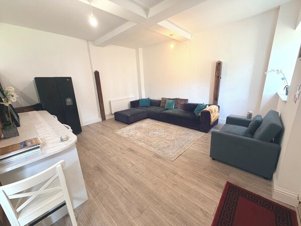 A modern living room with a sectional sofa, a coffee table, and a dining area with a white table and chairs.