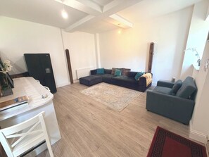 A modern living room with a sectional sofa, a coffee table, and a dining area with a white table and chairs.