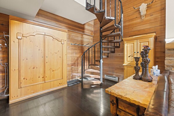 A wooden interior with a spiral staircase, a large wooden door, and a stone countertop with decorative items. - PERFECT MOUNTAIN RETREAT. (Breckenridge)