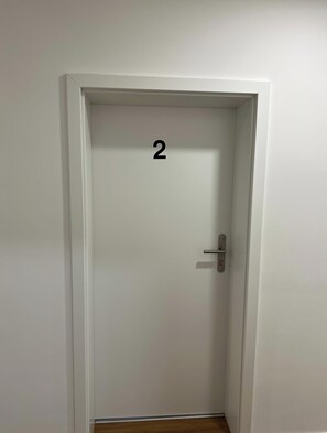 A white door with a number '2' on it, a door handle, and a wooden floor. - Stylish Apartment in a Prime Location in Nuremberg-Fürth (Fürth)