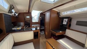 A compact interior with a kitchenette, a small dining area, and seating. - Sun Odyssey 349 - Vitamar (Polesana)